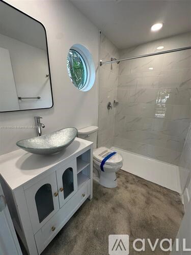 A bathroom with a round window and a white toilet.