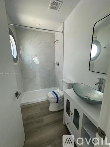 A bathroom with a round mirror and a round window.