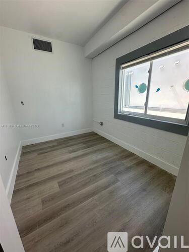 A room with wooden flooring and a window with a view of a street.