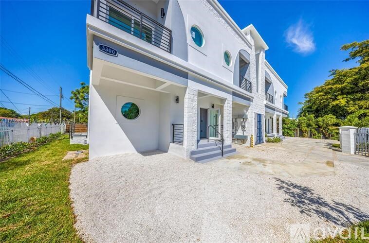 A white two-story house with a gravel driveway in front.
