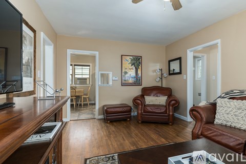 A living room with a brown leather couch and a wooden floor.