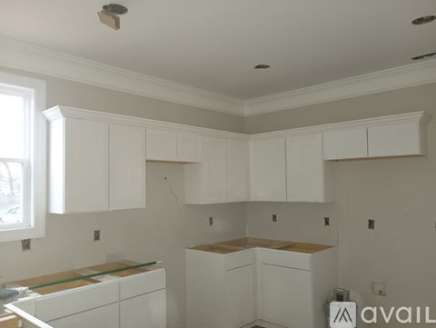 A kitchen with white cabinets and a countertop is available for rent.