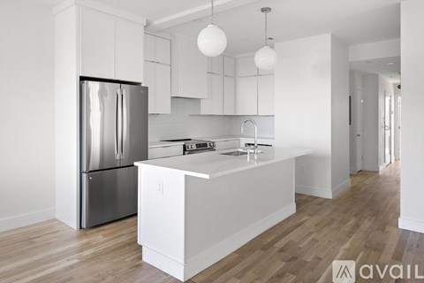 A modern kitchen with a stainless steel refrigerator and white cabinets.