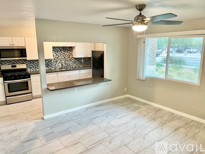 A kitchen with a stove top oven and a fan ceiling light.