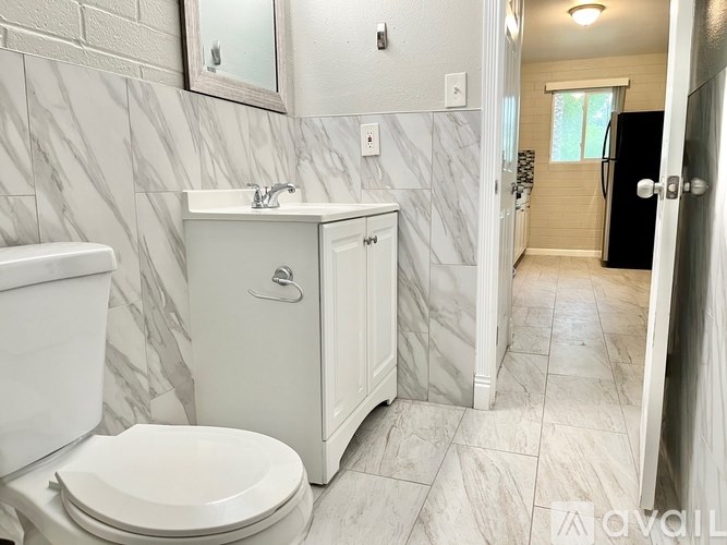 A bathroom with a toilet, sink, and mirror.