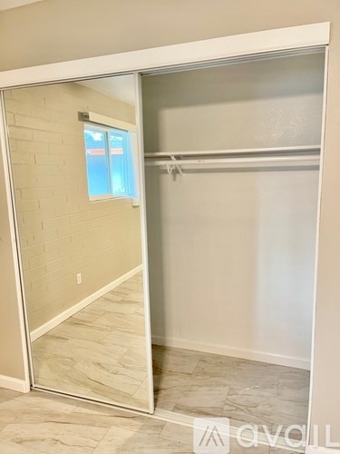 A white closet with a mirrored door and a brick wall in the background.