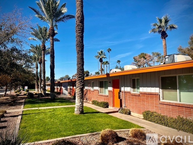 A row of palm trees in front of a building with orange trim.