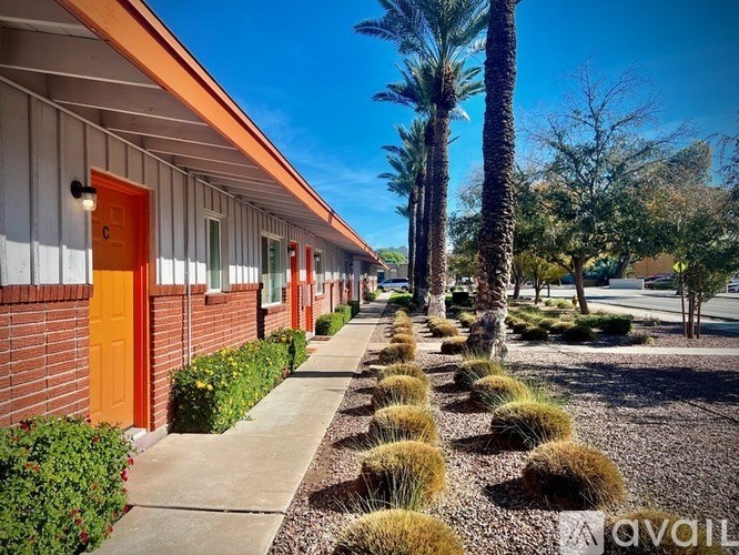 A row of houses with orange doors and a sidewalk in front.