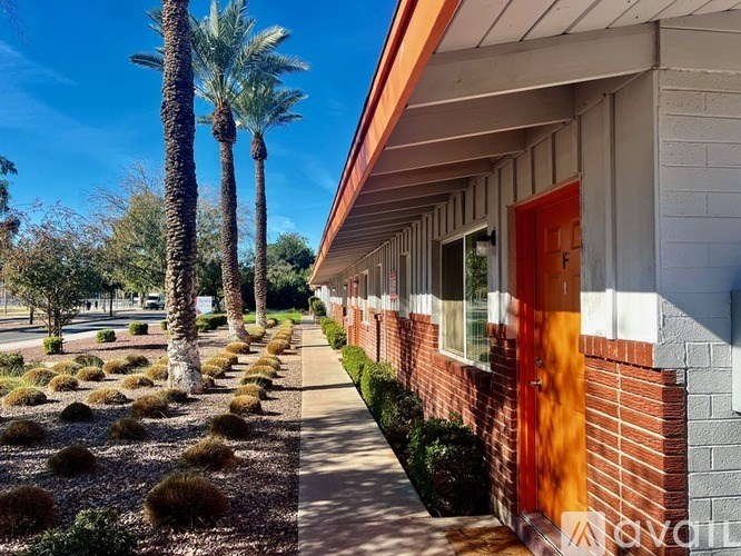 A row of houses with red doors and palm trees in the background.