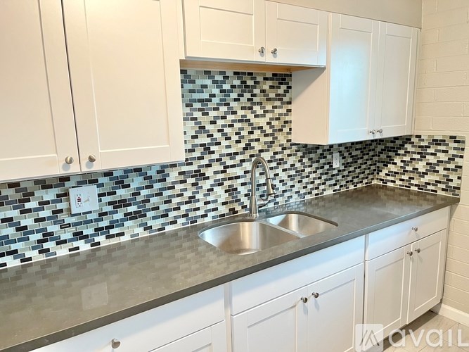 A kitchen with white cabinets and a black and white checkered backsplash.
