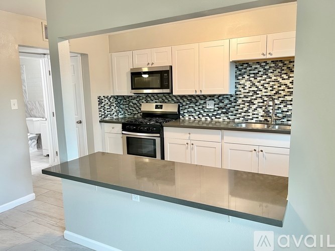 A kitchen with a black countertop and white cabinets.