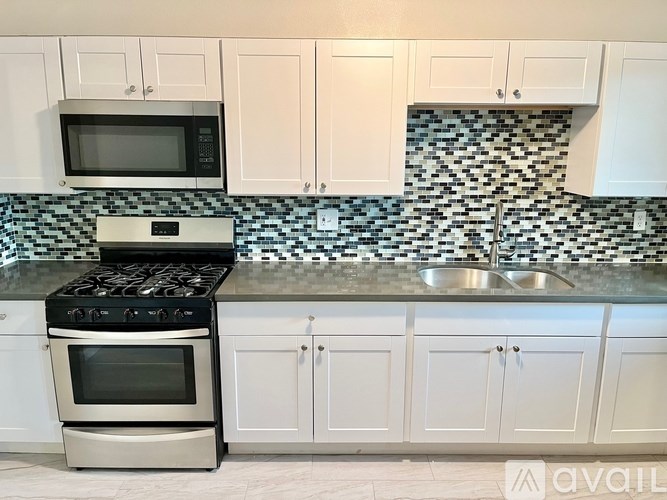 A kitchen with white cabinets and a black and white checkered backsplash.