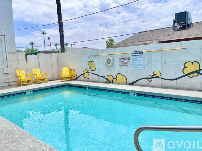A pool with a yellow chair and a wall with yellow flowers painted on it.