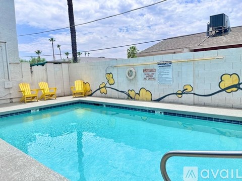 A pool with a yellow chair and a wall with yellow flowers painted on it.