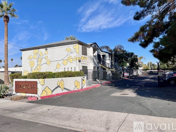 A sign that says Flower 22 in front of a building with yellow flowers painted on it.