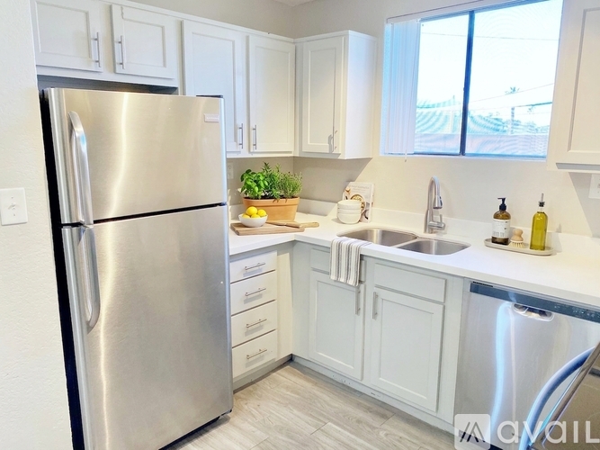 A kitchen with a stainless steel refrigerator and white cabinets.