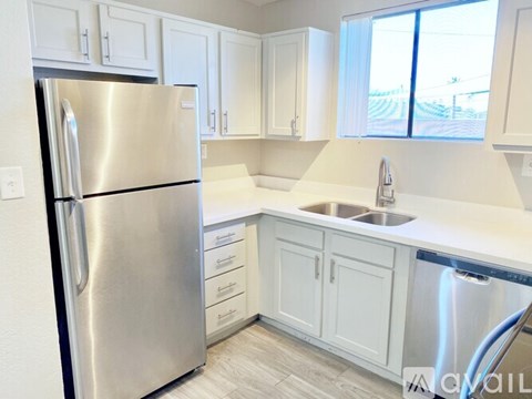 A kitchen with a stainless steel refrigerator and white cabinets.