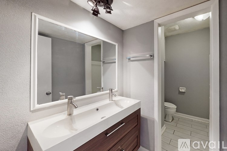 A bathroom with a white sink and brown drawers.