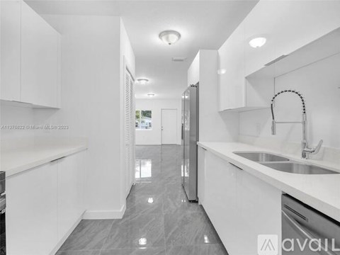 A modern kitchen with white cabinets and a grey floor.