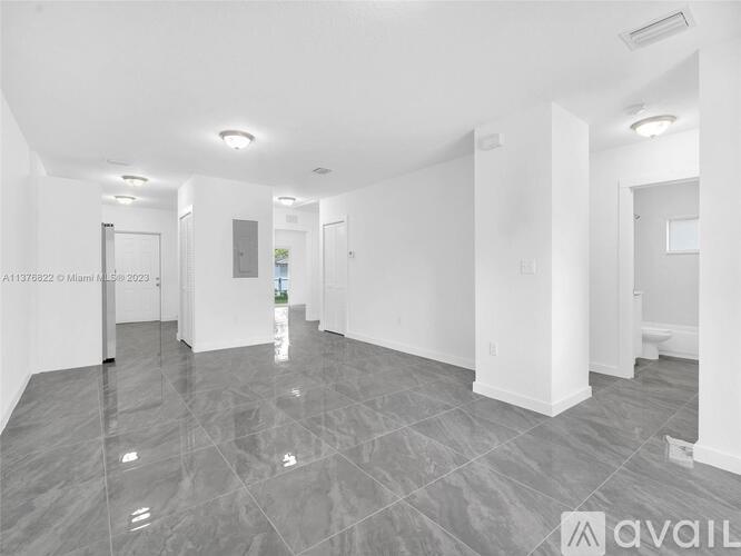 A spacious, empty room with grey tiled flooring and white walls.