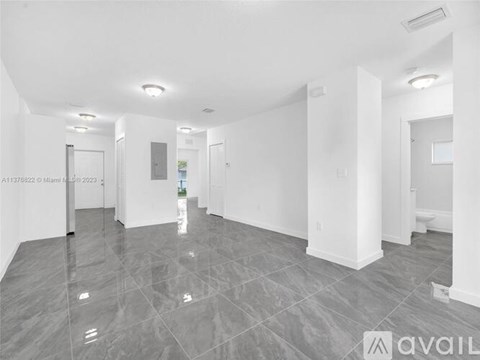A spacious, empty room with grey tiled flooring and white walls.