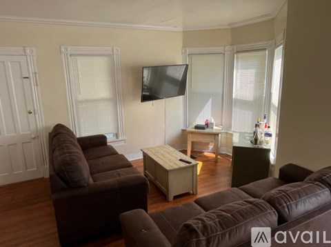 A living room with brown leather couches and a flat screen TV mounted on the wall.
