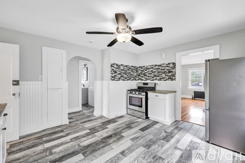 A kitchen with a fan on the ceiling and a refrigerator on the right.