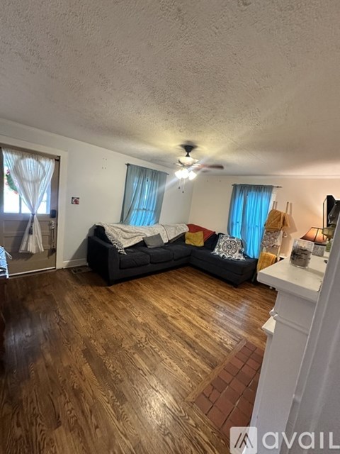 A living room with a black couch and wooden floors.