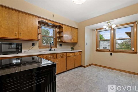 A kitchen with wooden cabinets and black countertops is available for rent.