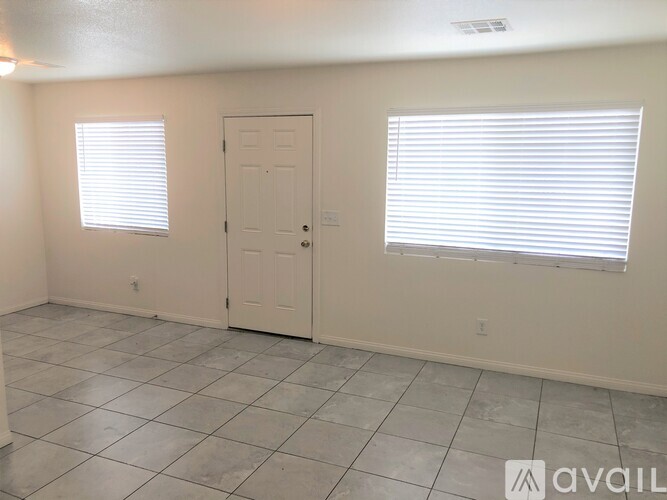 A room with a door, a window with blinds, and a tiled floor.