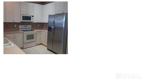 A kitchen with white cabinets and appliances.