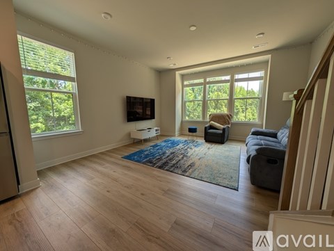 A living room with a blue rug and a television on the wall.