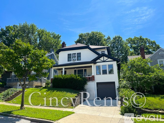A house with a white and black exterior is surrounded by greenery.