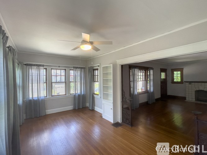 A spacious room with wooden floors and a ceiling fan.