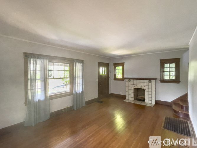 A room with a fireplace and a window with curtains.