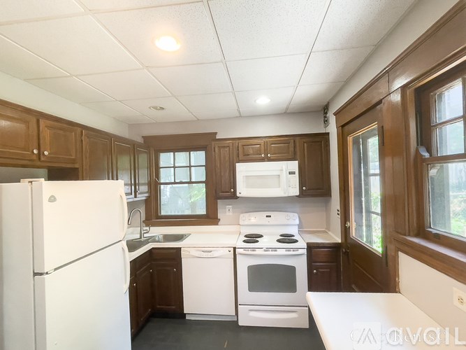 A kitchen with white appliances and wooden cabinets.