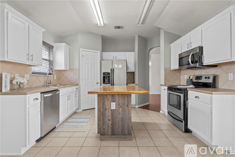 A kitchen with white cabinets and a wooden island in the middle.