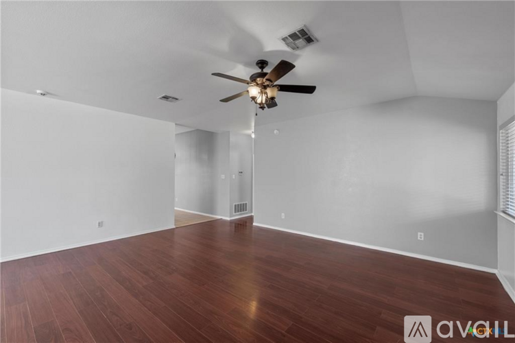 A room with a ceiling fan and wooden flooring.