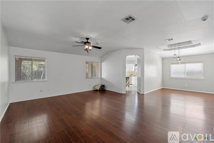 A spacious room with wooden floors and a ceiling fan.