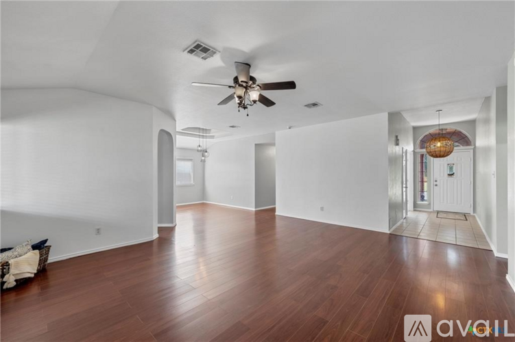 A spacious room with wooden floors and a ceiling fan.