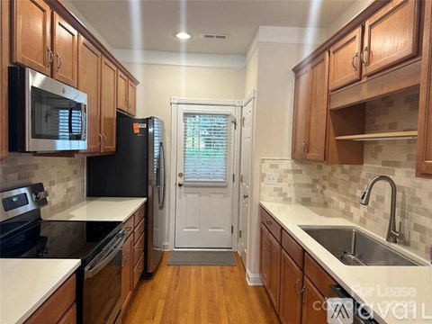 A kitchen with wooden cabinets and a black refrigerator.