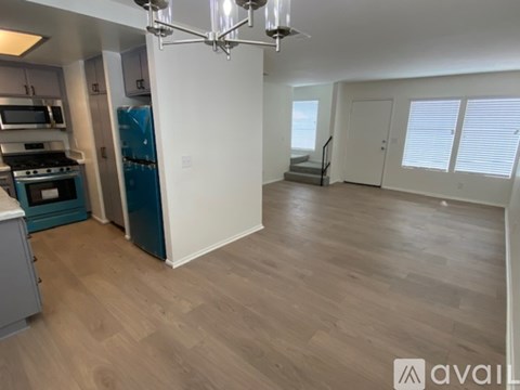 A kitchen with a blue refrigerator and wooden flooring.