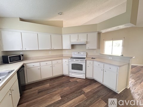 A kitchen with white cabinets and a wooden floor.
