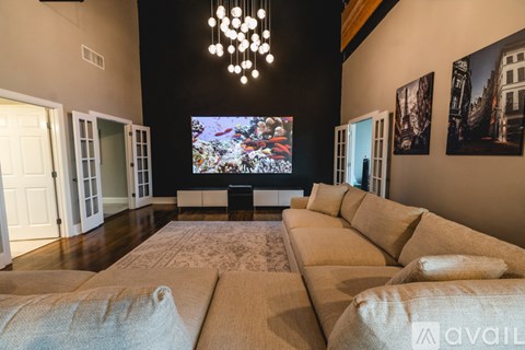 A living room with a large couch and a flat screen TV mounted on the wall.