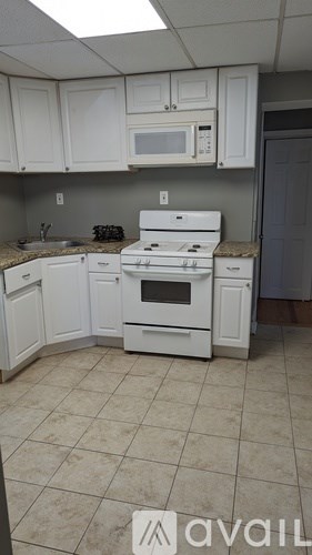 A kitchen with white cabinets and appliances is available for rent.