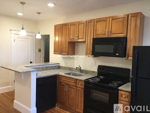 A kitchen with black appliances and wooden cabinets.