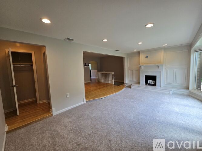A spacious living room with a fireplace and a large window.