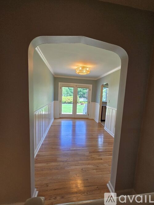 A hallway with wooden floors and white walls leading to a door.