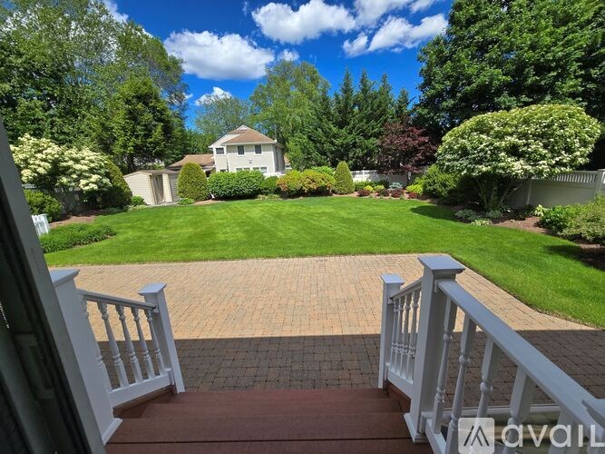A house with a white fence and a brick walkway leading to it.