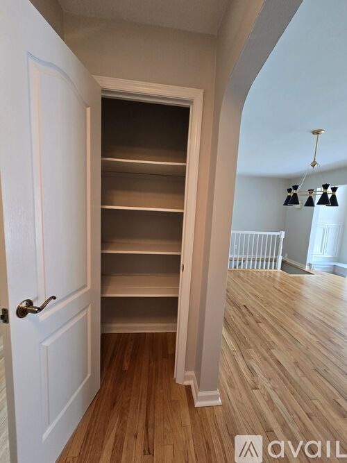 A white door with a handle is open to a hallway with a light fixture.
